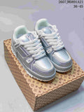 Pair of silver and white Louis Vuitton Trainer Maxi sneakers displayed on a patterned shoe box.
