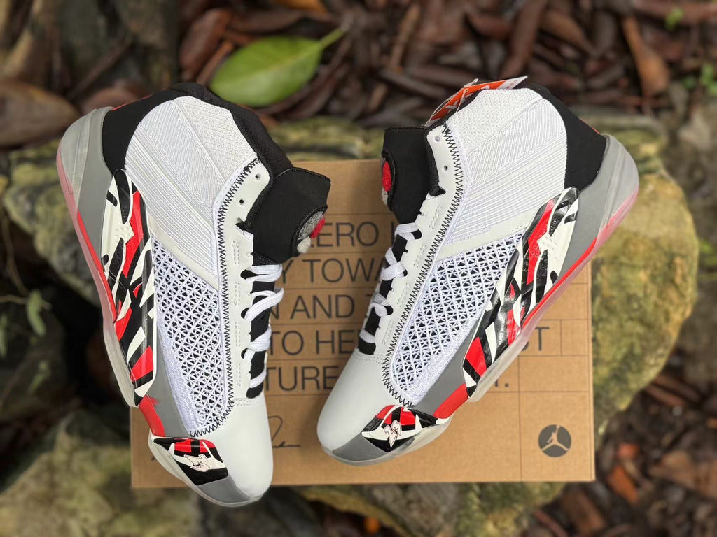 Overhead angled view of both shoes showing the white uppers, black tongues, and red and black side accents.