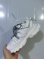 Side and rear view of the white sneaker showing its layered panels, lace system, and sculpted sole.