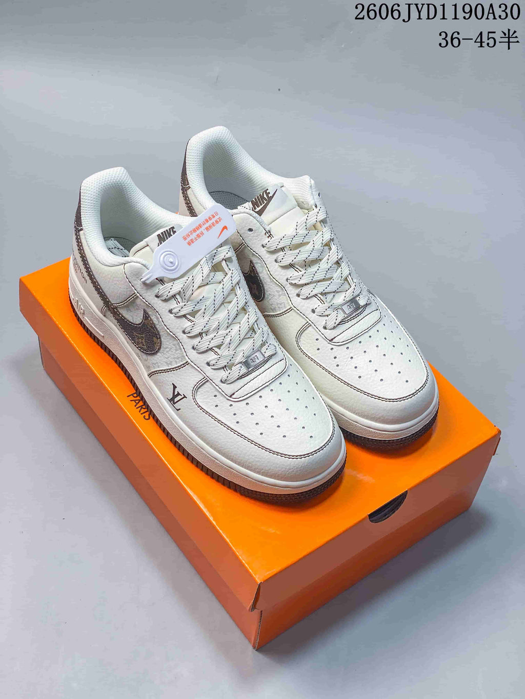Pair of cream low-top sneakers with dark patterned Swooshes and contrast stitching.