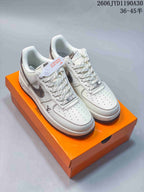 Pair of cream low-top sneakers with dark patterned Swooshes and contrast stitching.