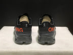 Rear view of the black sneakers showing padded collars, heel branding, and orange side graphics.