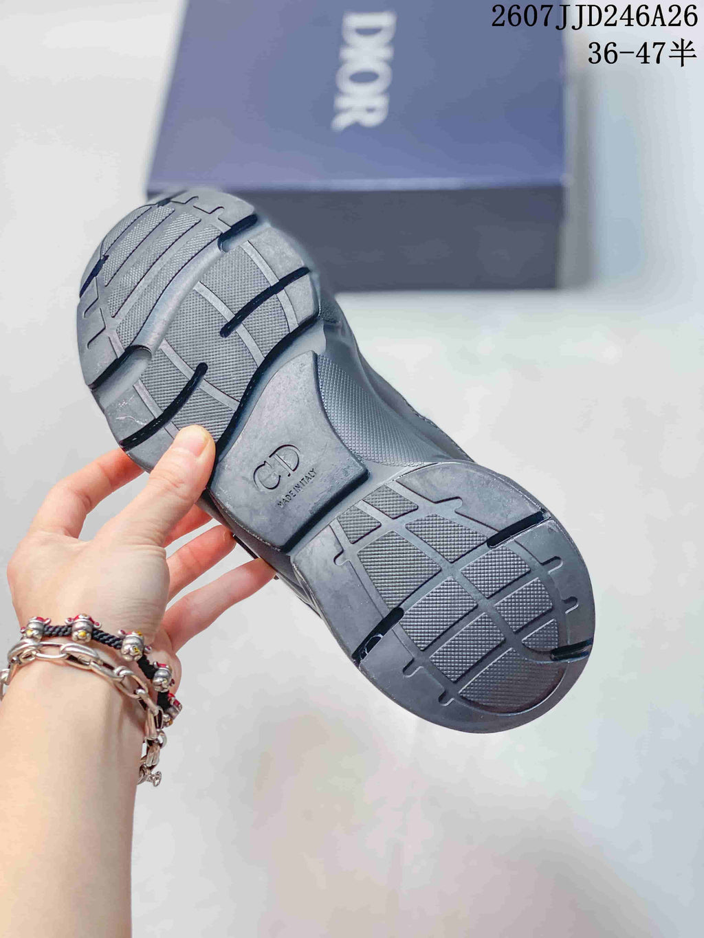 Underside view of a Dior sneaker showing the textured dark outsole and molded tread pattern.
