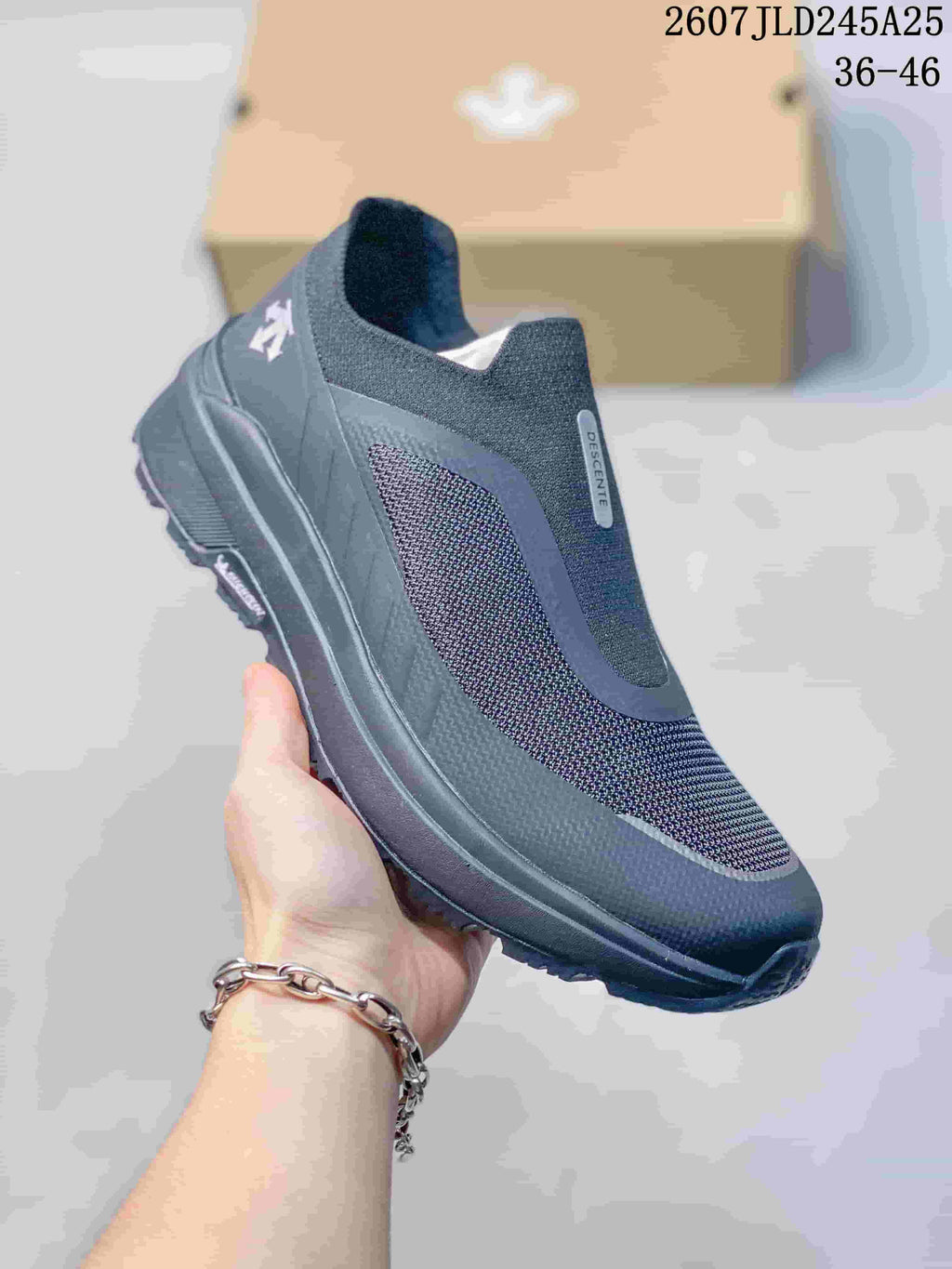 Angled side view of the dark navy and black DESCENTE sneaker showing the slip-on construction, side panel, heel branding, and treaded outsole; image text shows style code 2607JLD245A25 and size range 36–46.