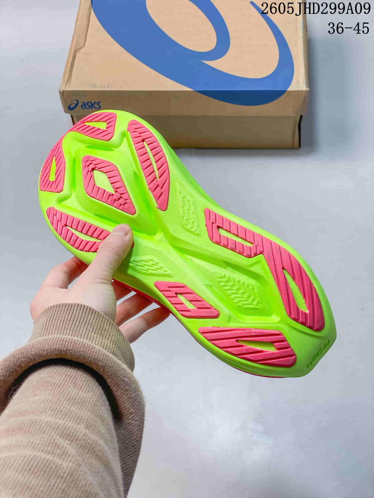 Close-up of the bright green outsole with pink rubber sections on an ASICS running shoe