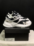 Side view of the white and black AMIRI MA Runner sneakers with layered panels and a chunky sculpted sole.