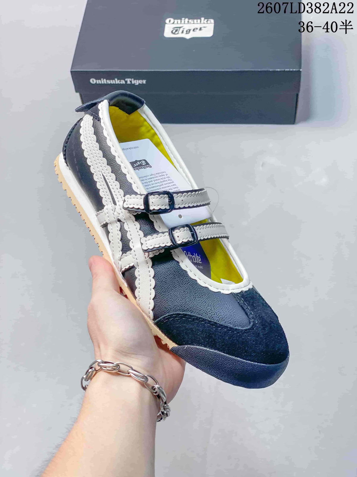 Close view of the navy and white shoe showing its layered side stripes, buckle straps, and rubber outsole.
