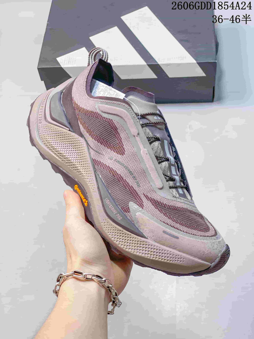 Side view of a mauve and gray trail running shoe with a chunky patterned sole
