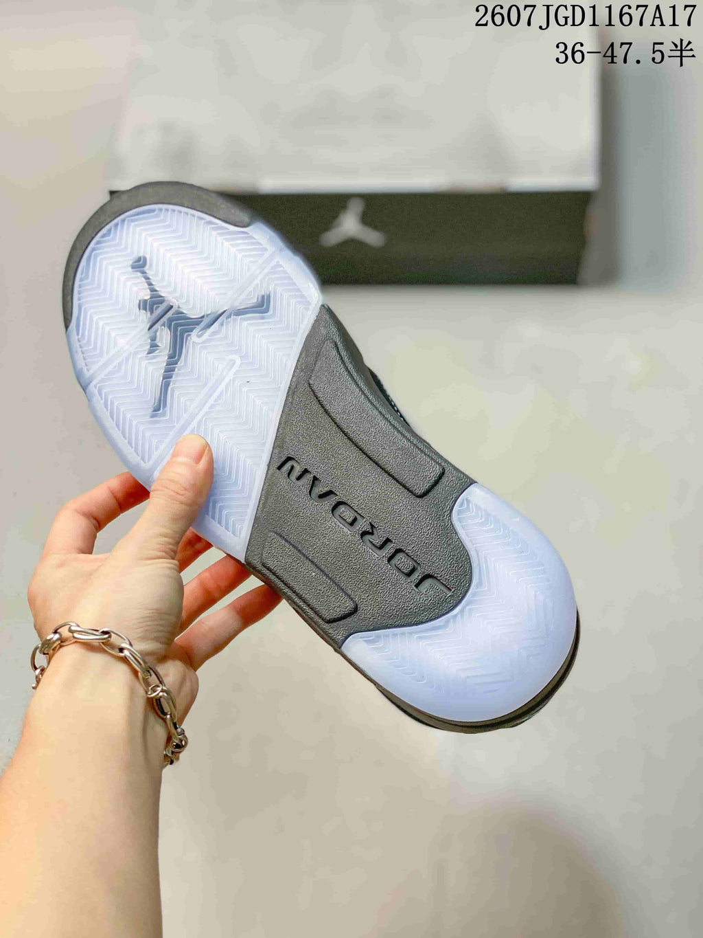 Underside view of a black sneaker showing the translucent outsole and herringbone-style tread pattern.
