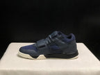Lateral side profile showing the dark upper, layered panels, side branding, strap, and cream outsole.