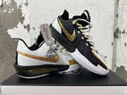 Pair of Nike basketball shoes showing contrasting white-and-gold and black-and-gold sides.