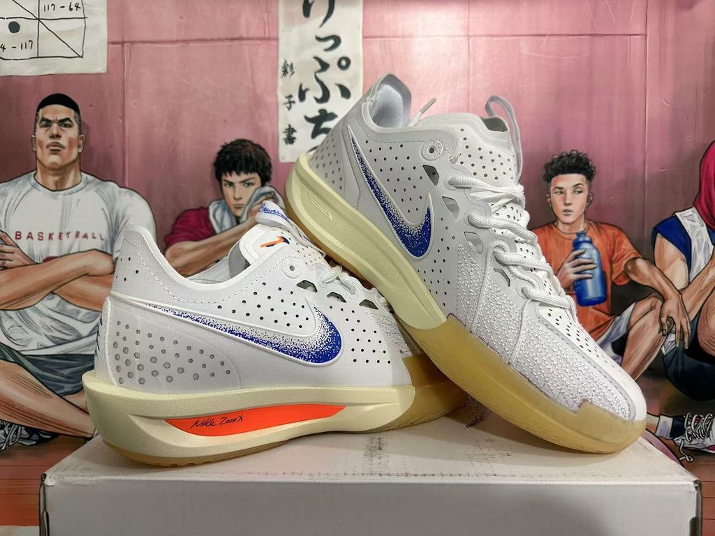 Angled view of a pair of white Nike basketball sneakers showing blue side branding, orange midsole details, and gum-colored outsoles.