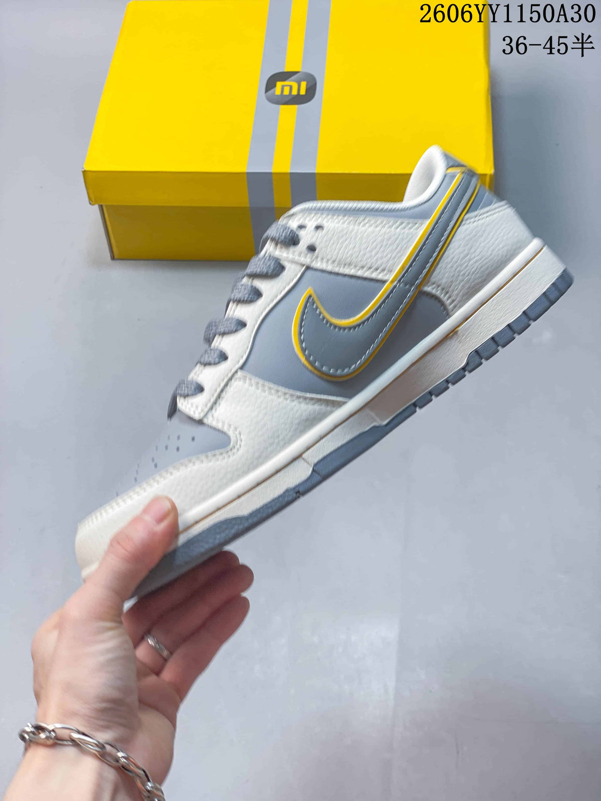 Side view of a grey, white, and yellow Nike SB Dunk Low sneaker