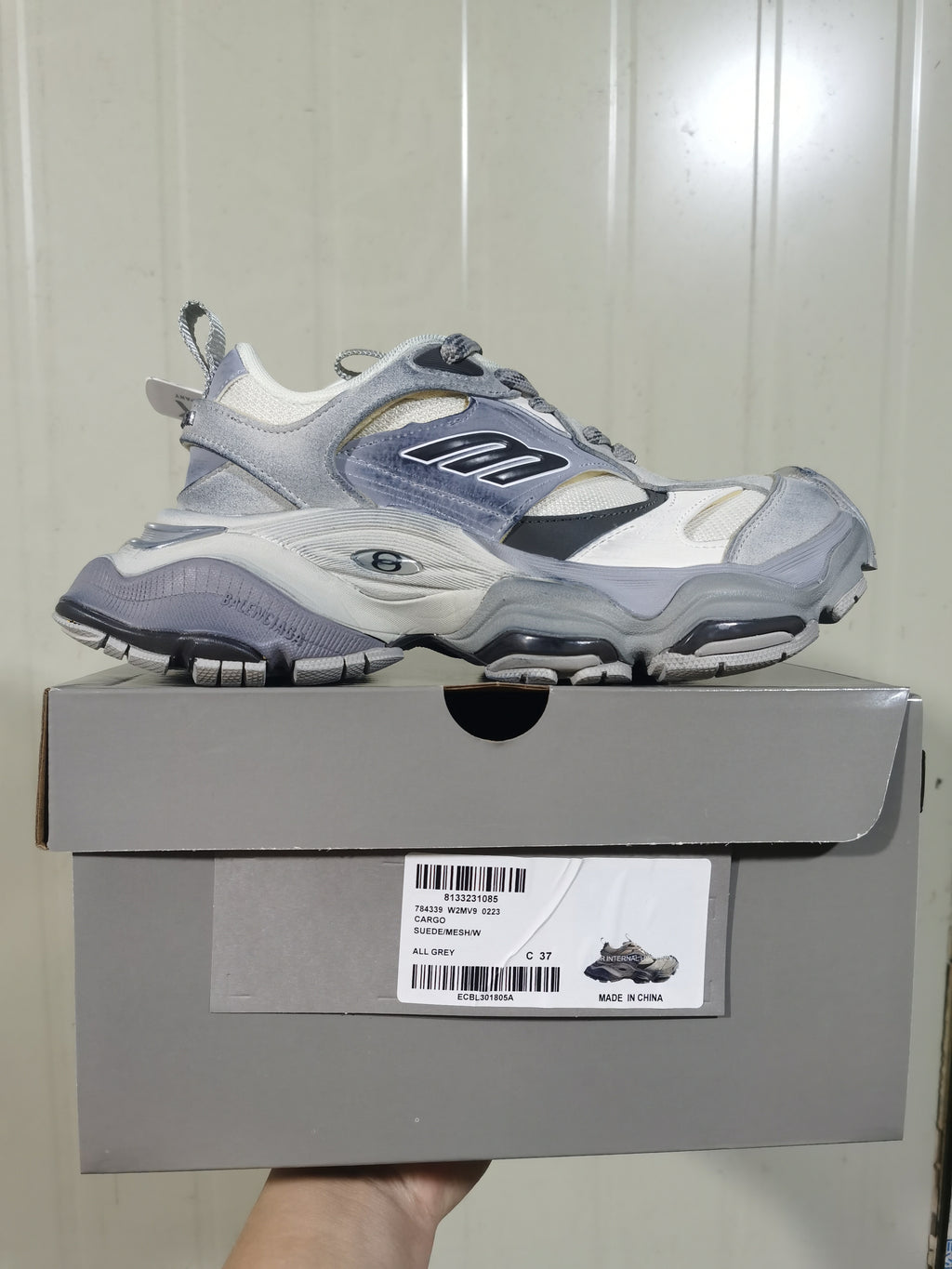 Side view of the all-grey sneaker resting on its box; the box label shows CARGO, SUEDE/MESH/W, ALL GREY, and size C 37.
