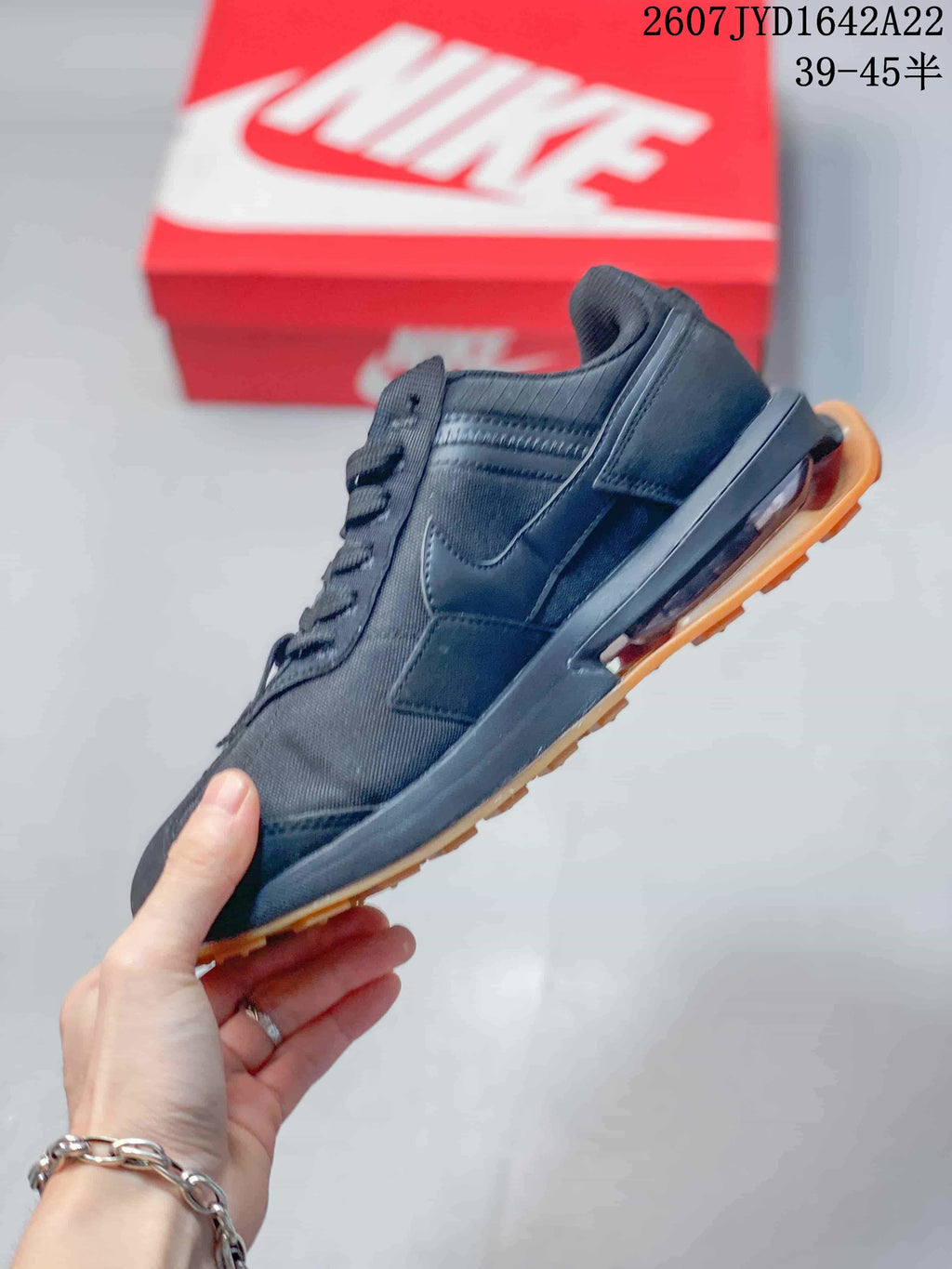 Side profile of the black low-top sneaker showing layered panels, side branding and the heel air unit.