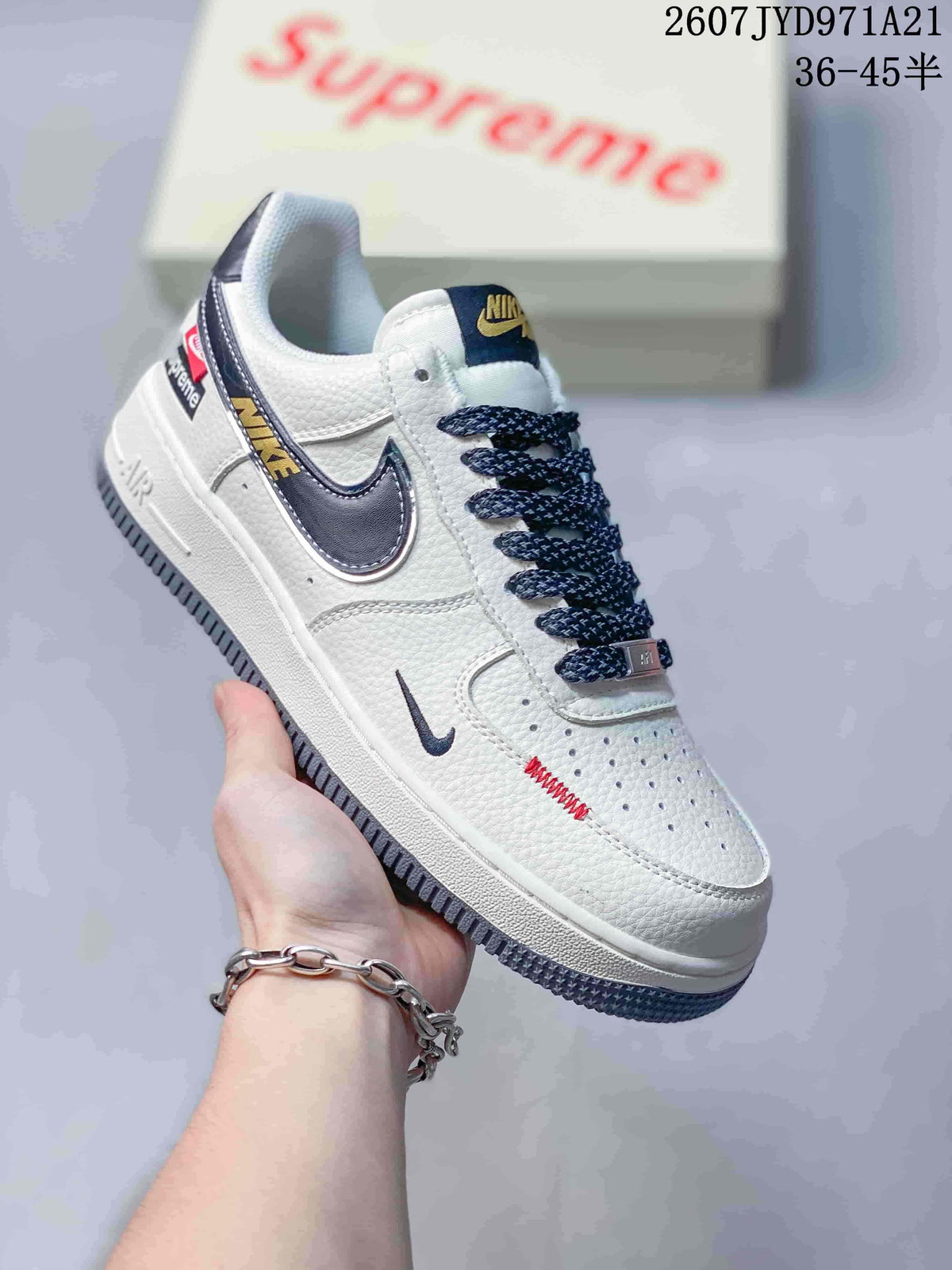 Angled side view showing the white upper, navy Swoosh and heel accents, patterned laces and grey outsole.