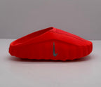 Side view of an orange-red Nike slide showing the raised sole and side Swoosh.