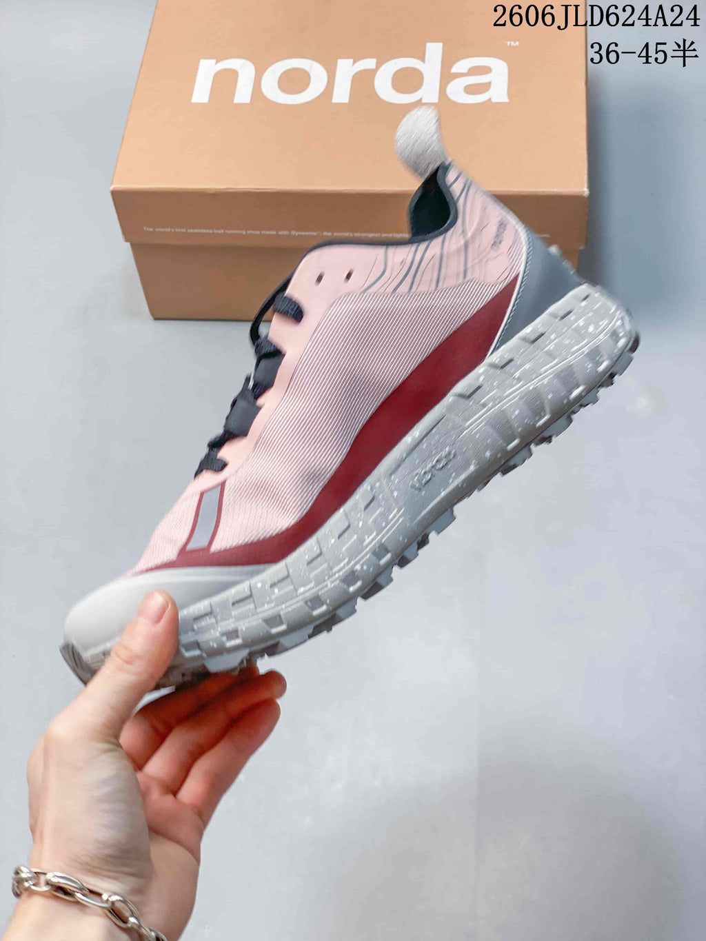 Side view of the pink shoe with gray treaded outsole and burgundy accent