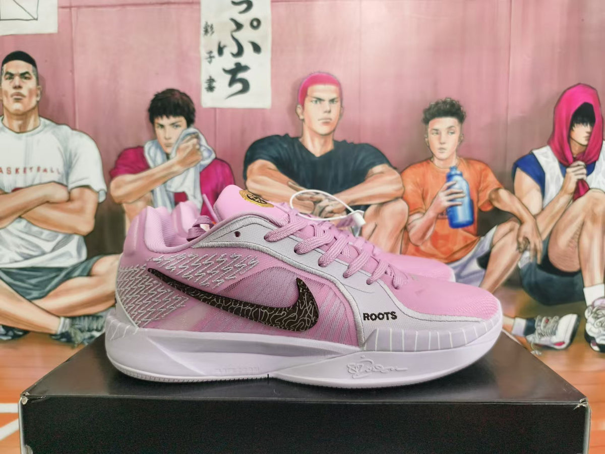 Side view of pink and light gray shoes with a dark patterned Swoosh and ROOTS lettering