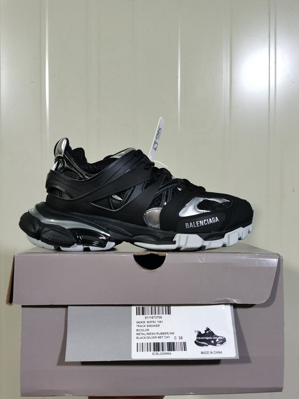 Black and silver Balenciaga sneaker displayed on its product box, with the box label showing style code 1081 and size C 38.