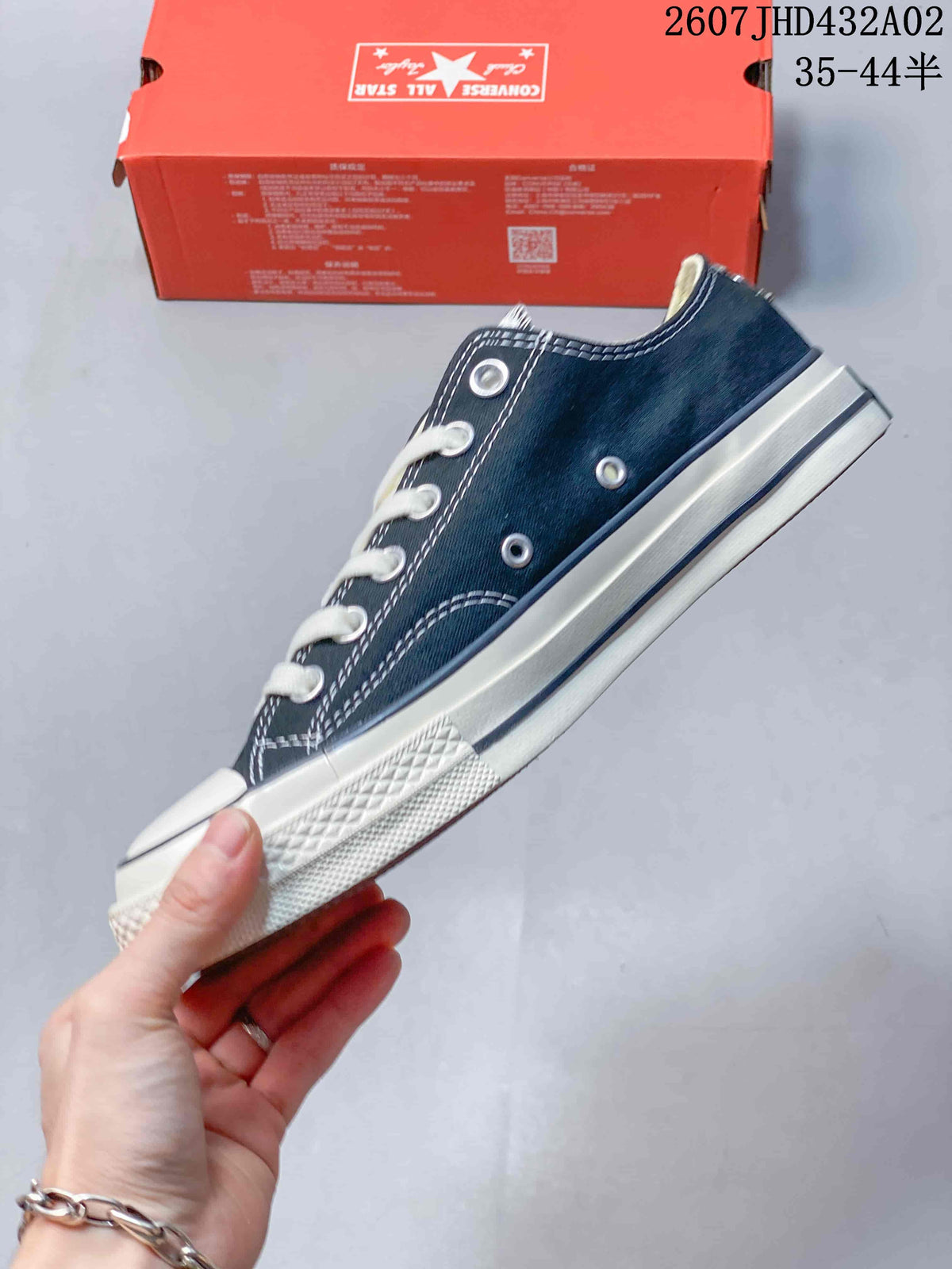 Side view of the navy low-top sneaker with white contrast stitching, metal eyelets, and a white sole.