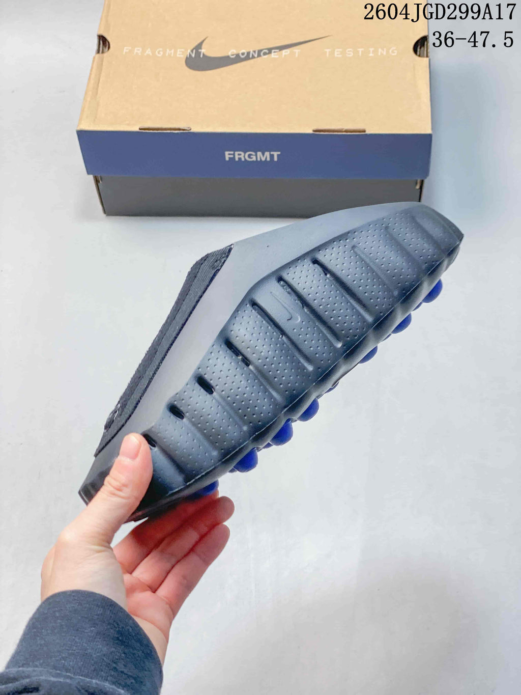 Side profile of the slide showing the perforated upper, rounded outsole, and blue elements beneath the sole.