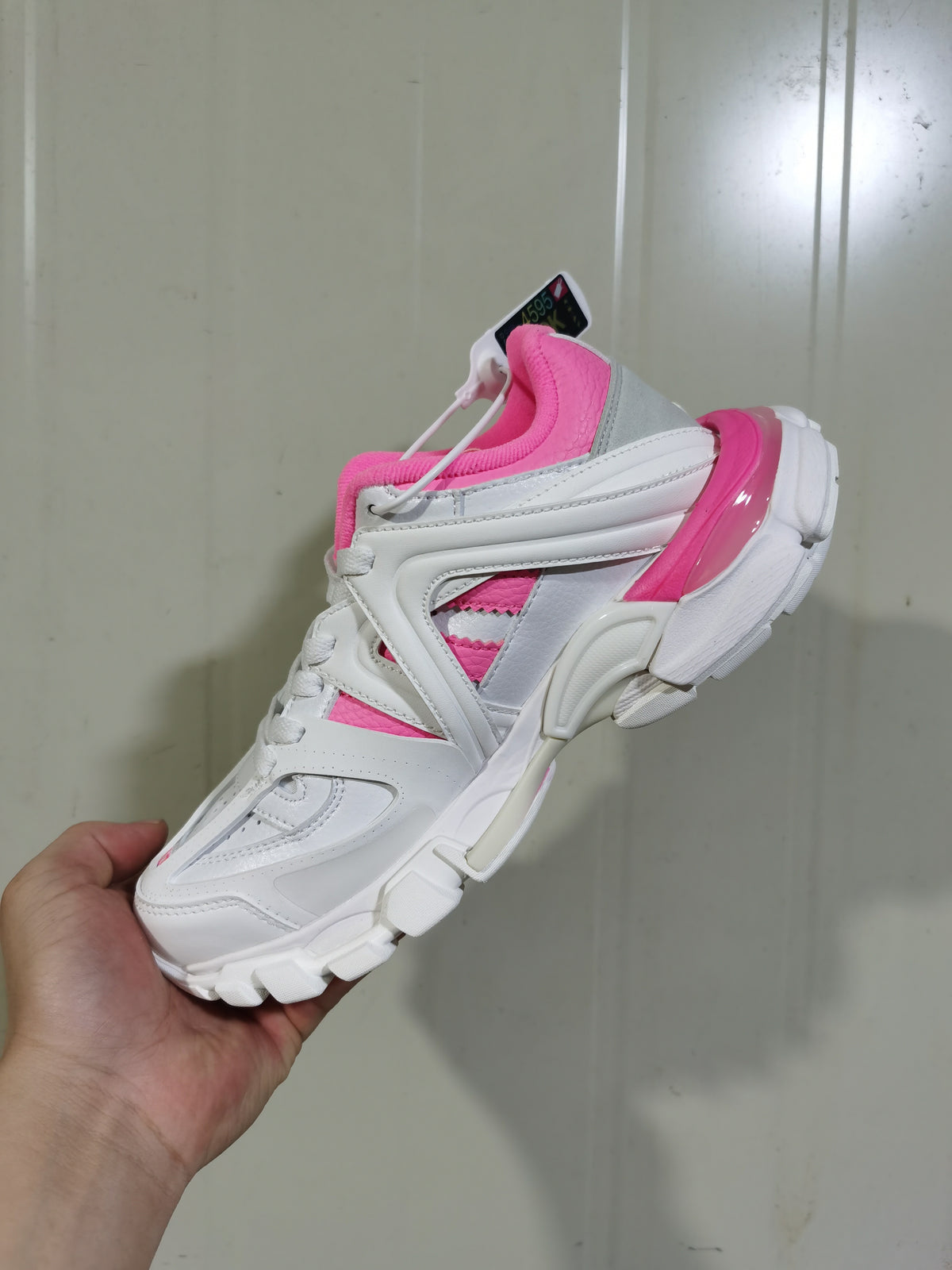 Side and top view of the white and pink sneaker showing grey detailing, lace-up fastening, and a chunky segmented outsole.