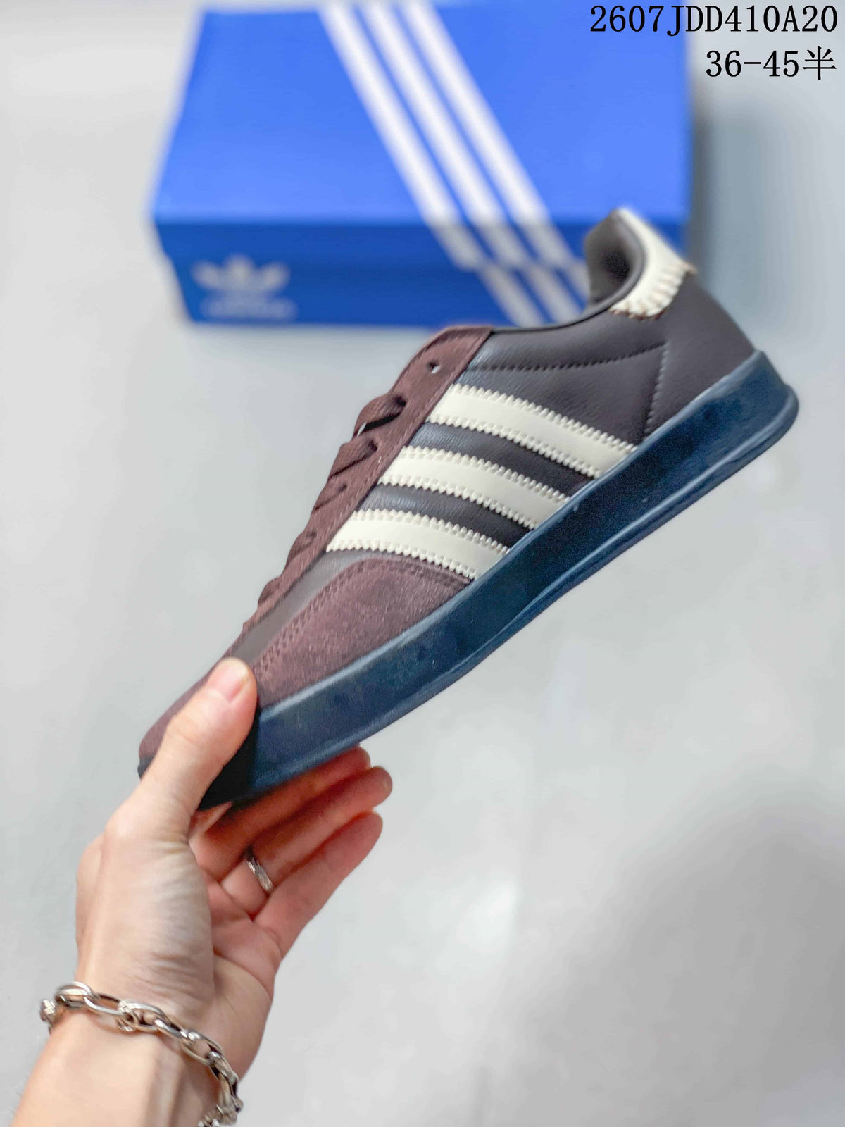 Side profile showing the brown upper, cream three stripes, dark sole, and low-top shape.