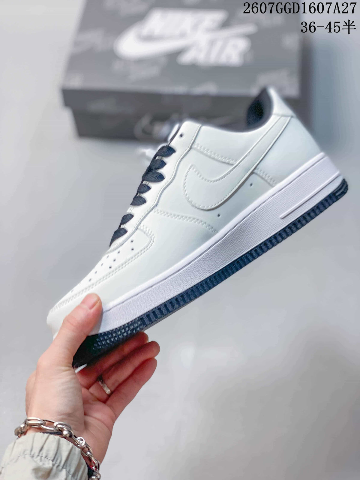 Side profile of the white low-top sneaker with a Nike Swoosh, perforated toe, dark laces, and contrasting outsole.
