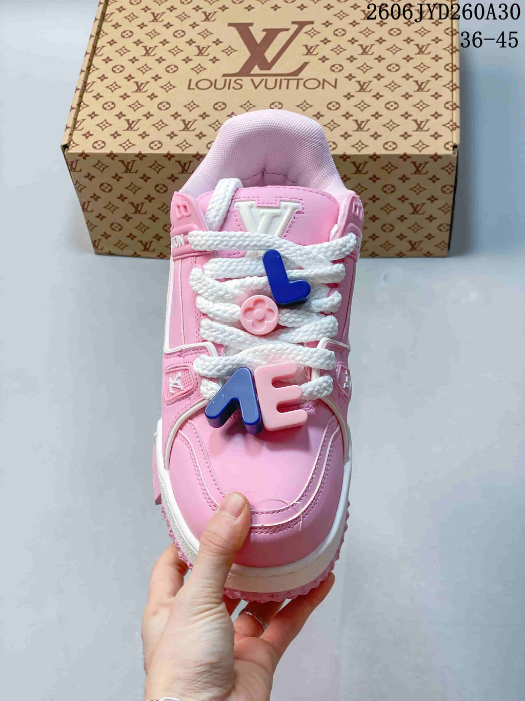 Top view of a pink Trainer Maxi sneaker with white laces and colorful decorative charms.