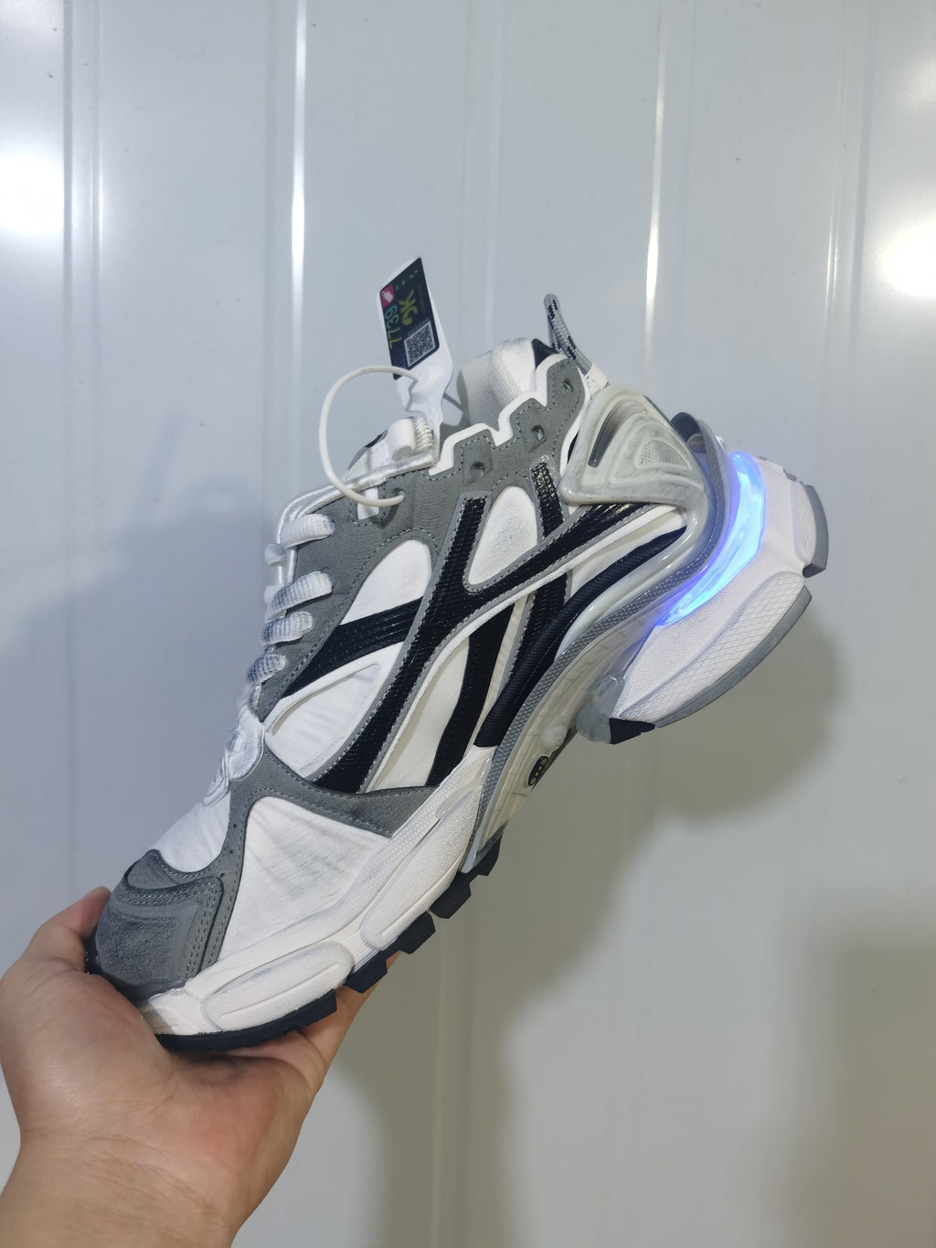 Side view of grey, white, and black Puma 9012 sneakers with a blue illuminated heel accent.