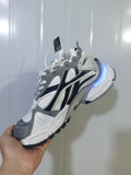 Side view of grey, white, and black Puma 9012 sneakers with a blue illuminated heel accent.