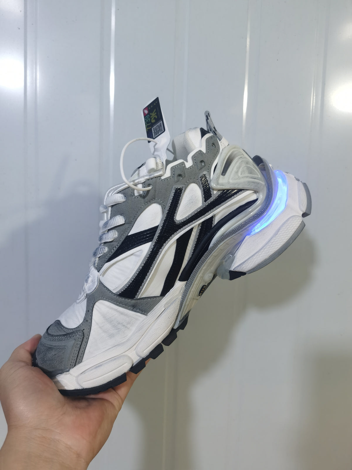 Side view of grey, white, and black Puma 9012 sneakers with a blue illuminated heel accent.