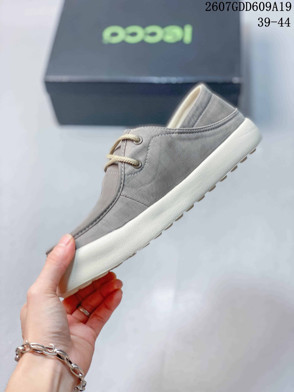 Side profile of the gray low-top sneaker showing the lace-up upper, stitched panels, and light-colored sole.