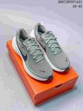 Pair of gray and muted green Nike Vomero 18 sneakers displayed on an orange Nike shoebox.