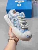Close-up of a blue-and-white Ouder sneaker showing textured panels and the rounded toe.