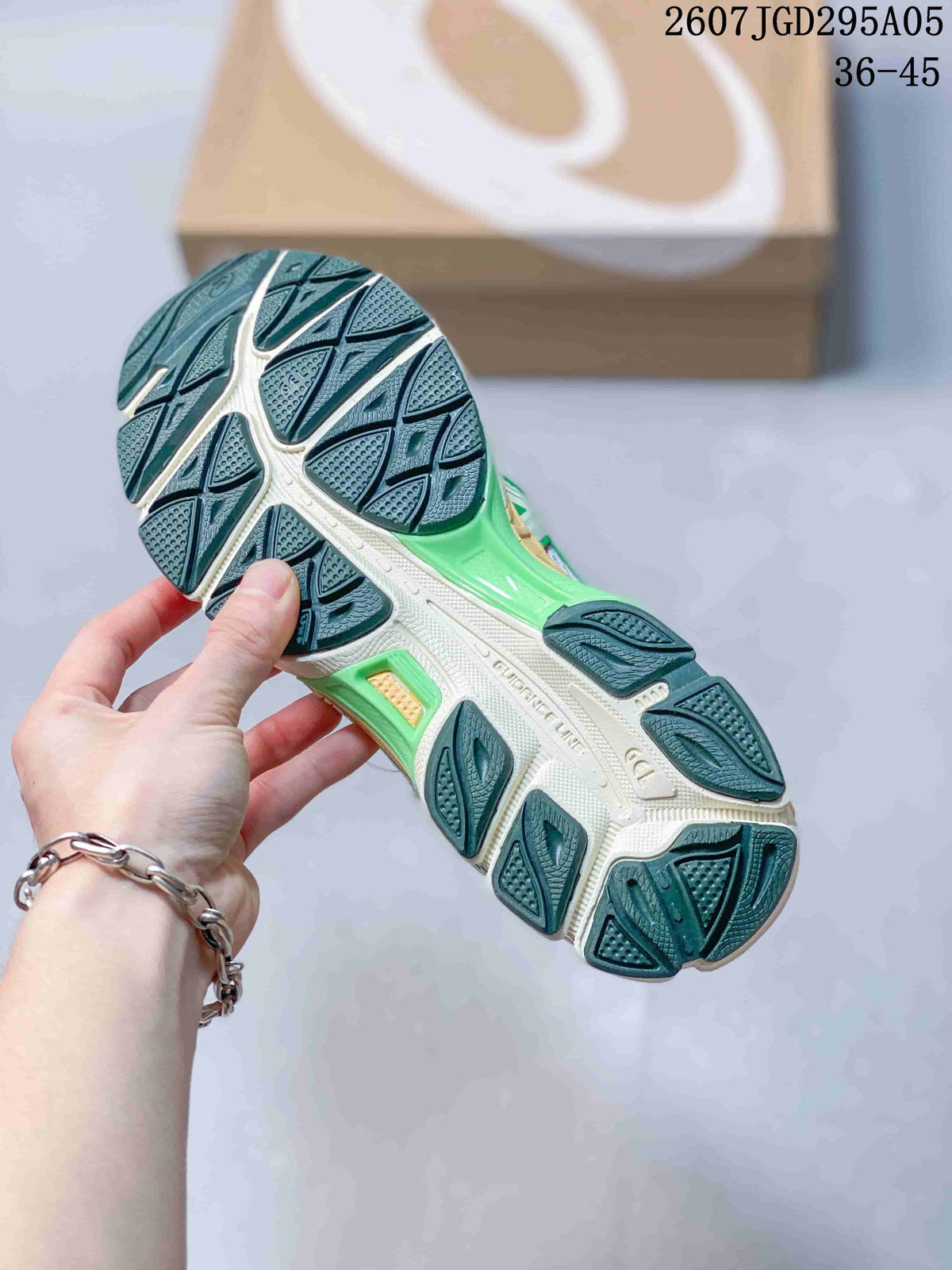Close view of the patterned outsole, showing segmented dark green traction sections and a light-colored midsole.