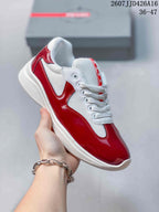Angled side view of a red and white Prada-branded sneaker with glossy overlays and a raised white sole.