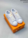 Pair of white Nike Blazer Low Premium sneakers displayed on an orange shoebox.