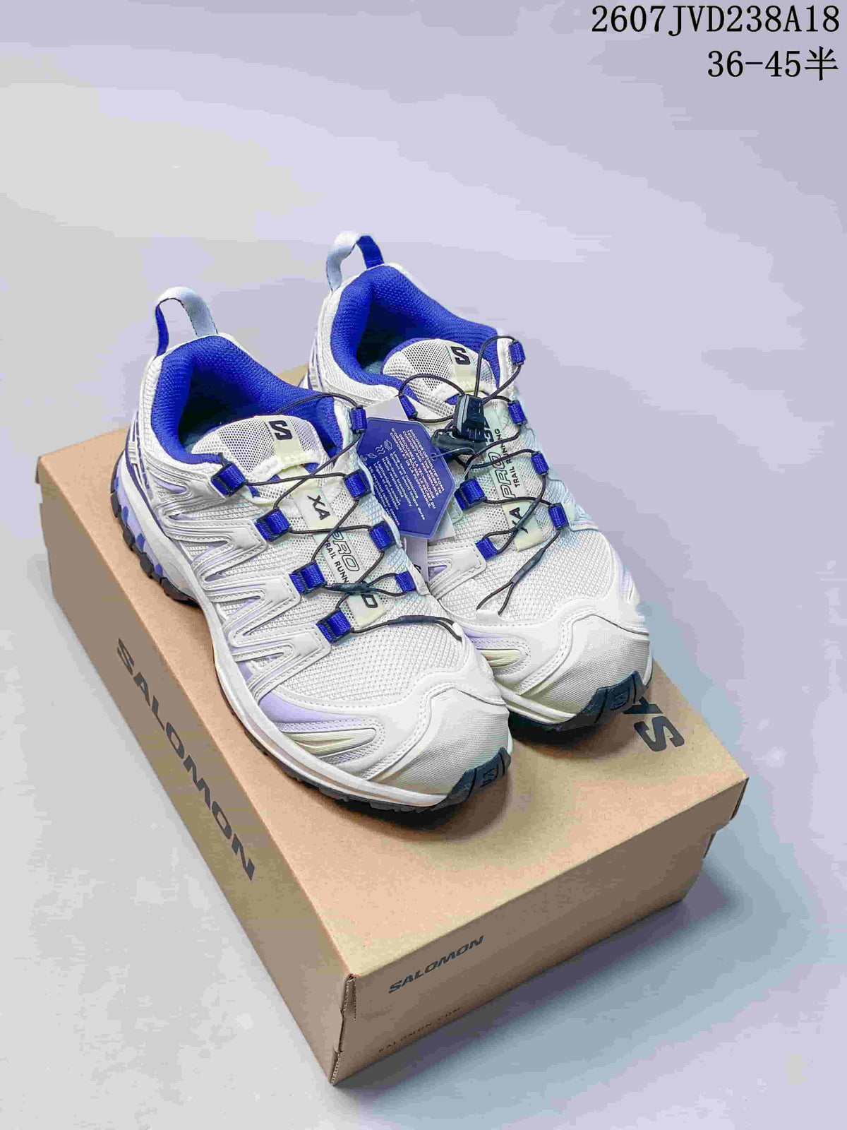 Pair of white and blue Salomon XA Pro 3D V9 shoes displayed on a Salomon shoe box.