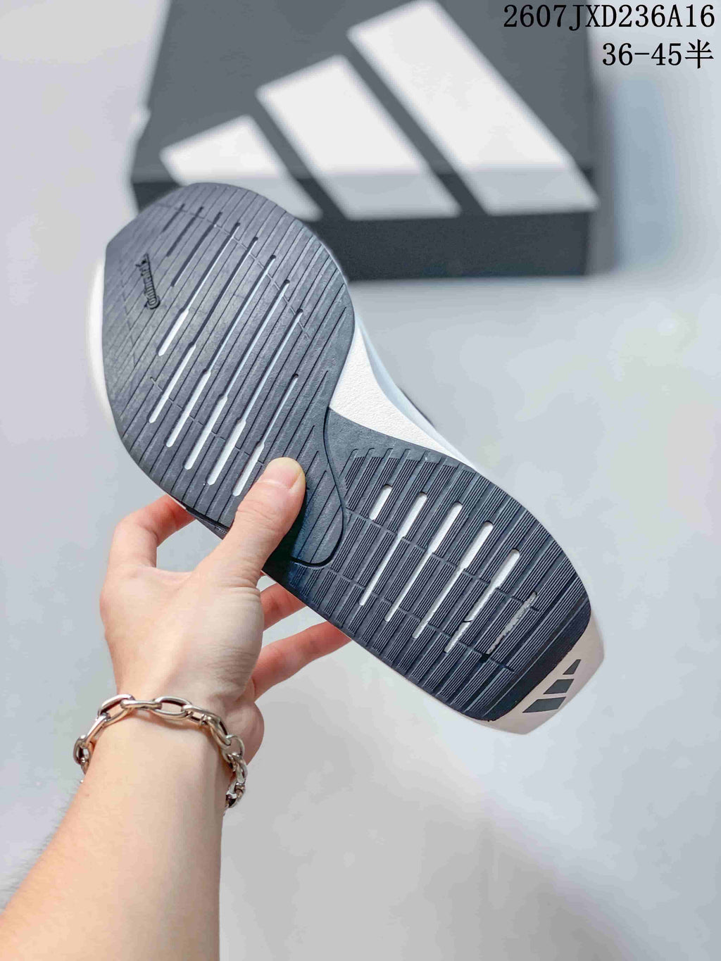 Underside view of the shoe showing a dark rubber outsole with linear grooves and contrasting white traction sections.