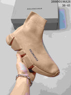 Angled front-side view of a beige Balenciaga knit sock sneaker with visible upper branding and segmented outsole.
