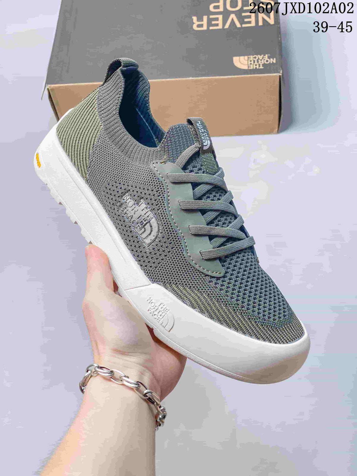 Close-up of a gray and olive The North Face Dune sneaker showing its knit-look upper and sole.
