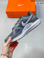Side profile of a gray Nike running sneaker with white Swoosh branding, mesh upper, and white midsole.