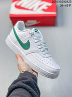 White Nike Court Vision Low sneaker with a green Swoosh and green tongue detail.