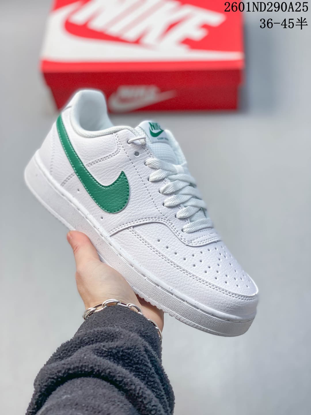 White Nike Court Vision Low sneaker with a green Swoosh and green tongue detail.