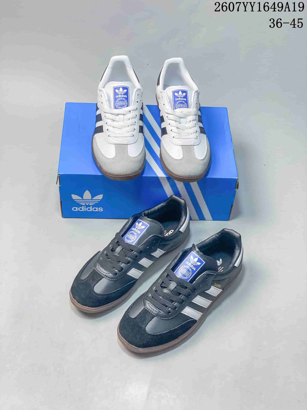 White and black Adidas Samba sneakers shown together with a blue Adidas shoebox.