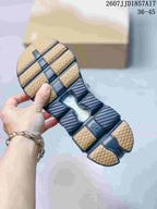 Outsole view of a gray and black sneaker showing segmented dark cushioning sections and tan rubber traction areas.