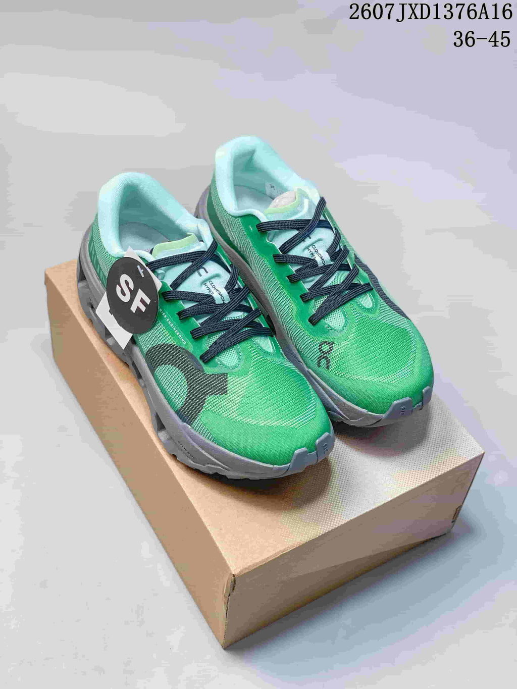 Pair of green On Cloudmonster 3 Hyper sneakers displayed on a shoebox, showing black laces and gray soles.