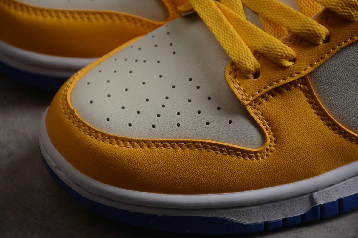 Close-up of the perforated light-colored toe box, wheat gold overlay, stitching, and blue outsole edge.